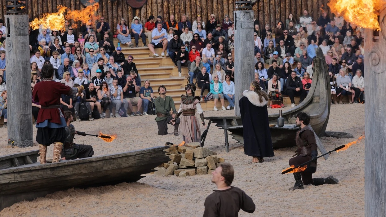 Viking-themed performance at Kynren with actors and flaming torches, audience in background.