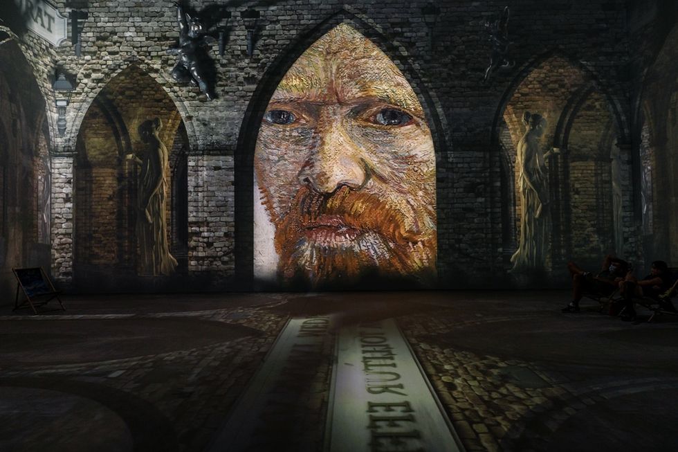 Vincent Van Gogh portrait projected on stone arches inside a dimly lit room at Van Gogh: The Immersive Experience in Cincinnati, US.