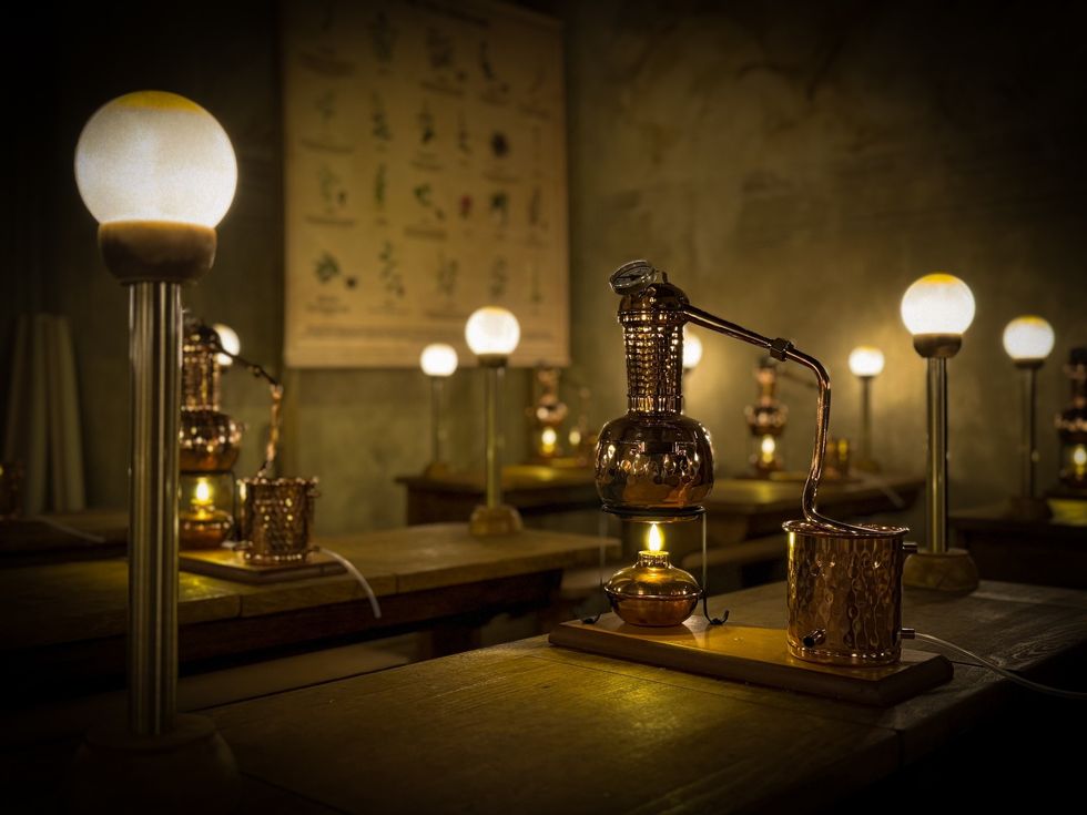 Vintage distillation setup with glowing lamps on a wooden table.
