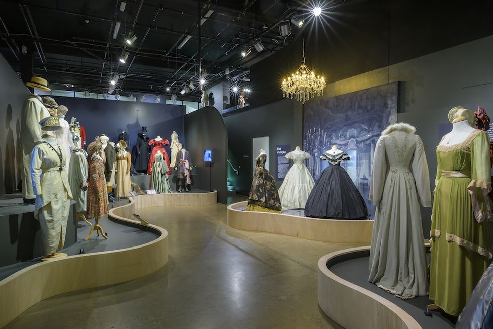 Vintage fashion exhibit. Costume Couture, with mannequins in elegant, historical costumes under a chandelier.