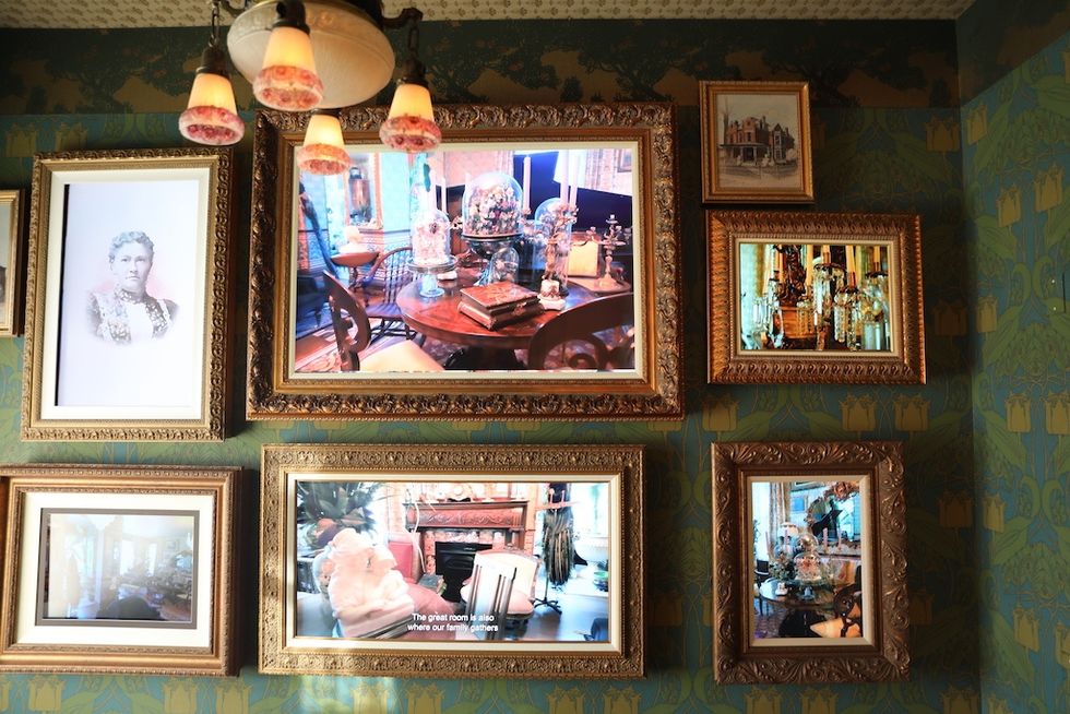 Vintage frames display art and photographs on a patterned wallpapered wall in Schifferdecker and Zelleken homes