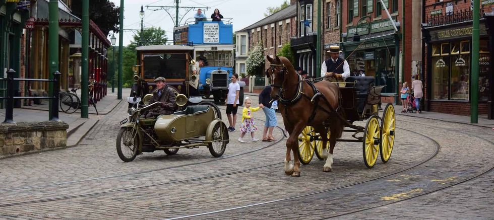 Vintage street scene at beamish Museum, with horse carriage, sidecar motorcycle, and historic tram.