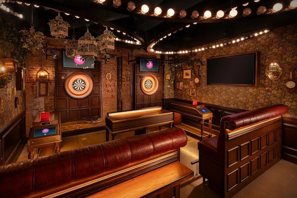 Vintage-style dart room with wooden decor and leather seating, adorned with soft lighting.