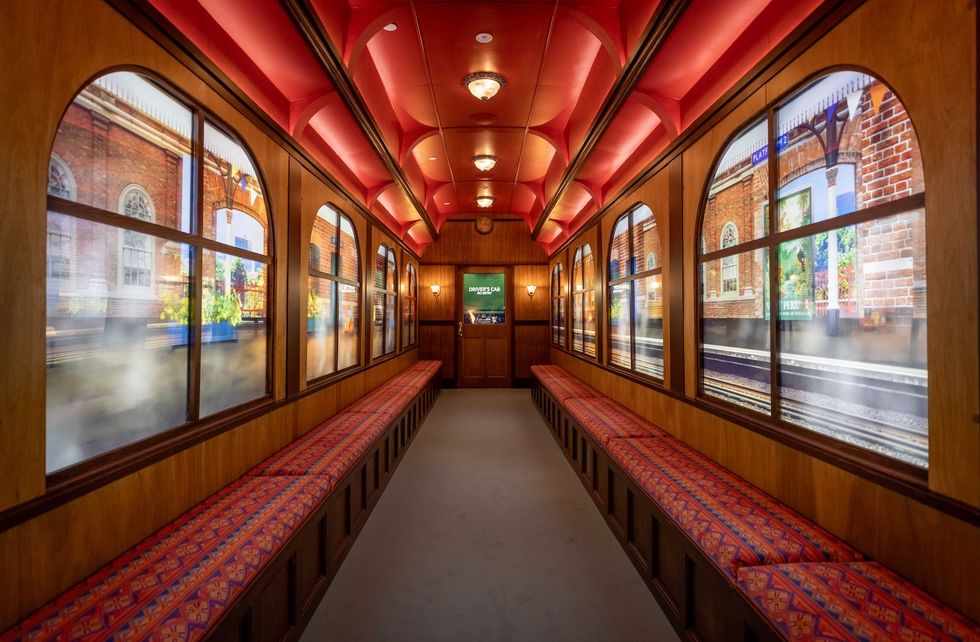 Vintage train carriage interior with patterned seats and scenic window screens.