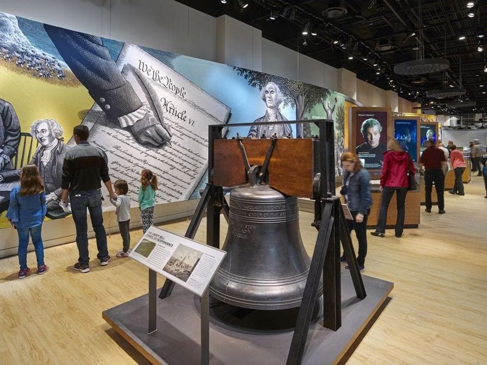 Visitors exploring the exhibit with a bell located in the middle