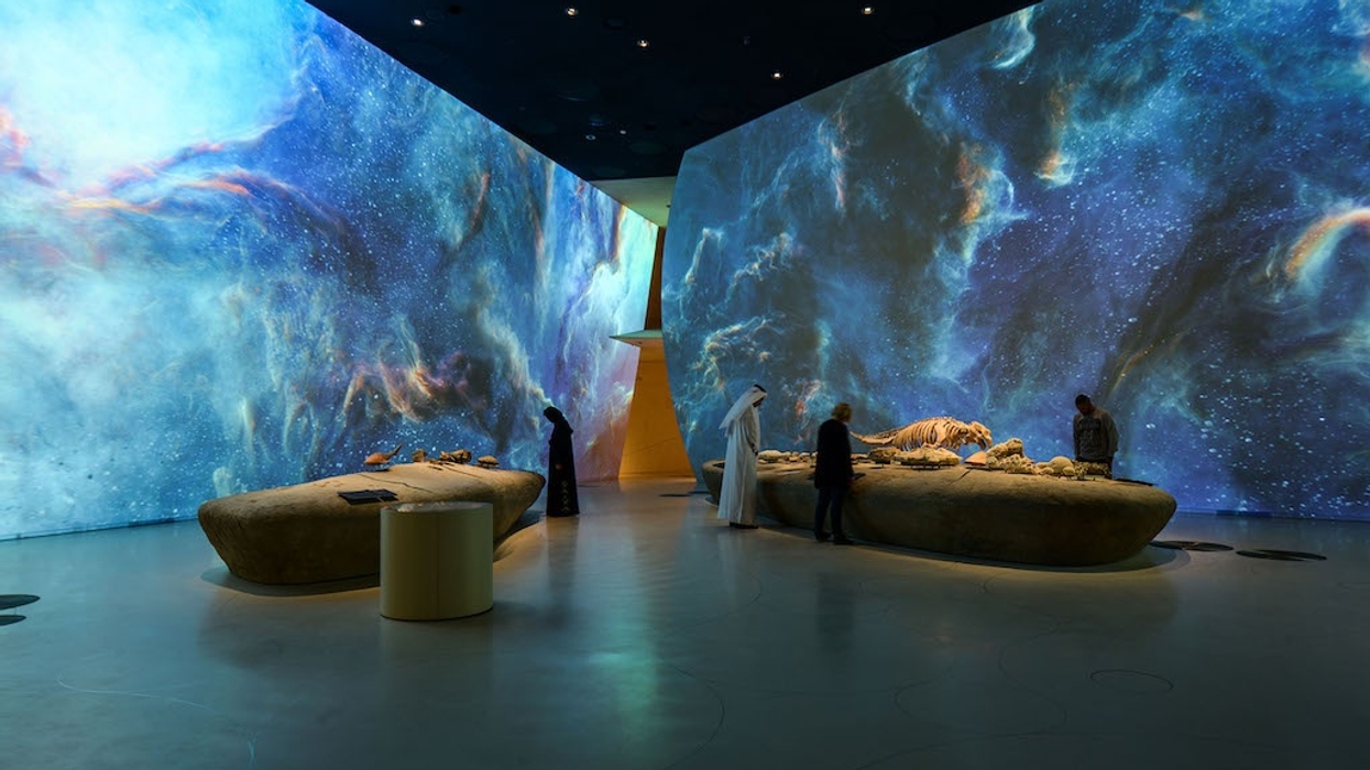 Visitors in a cosmic-themed exhibit with large galaxy visuals on the walls.