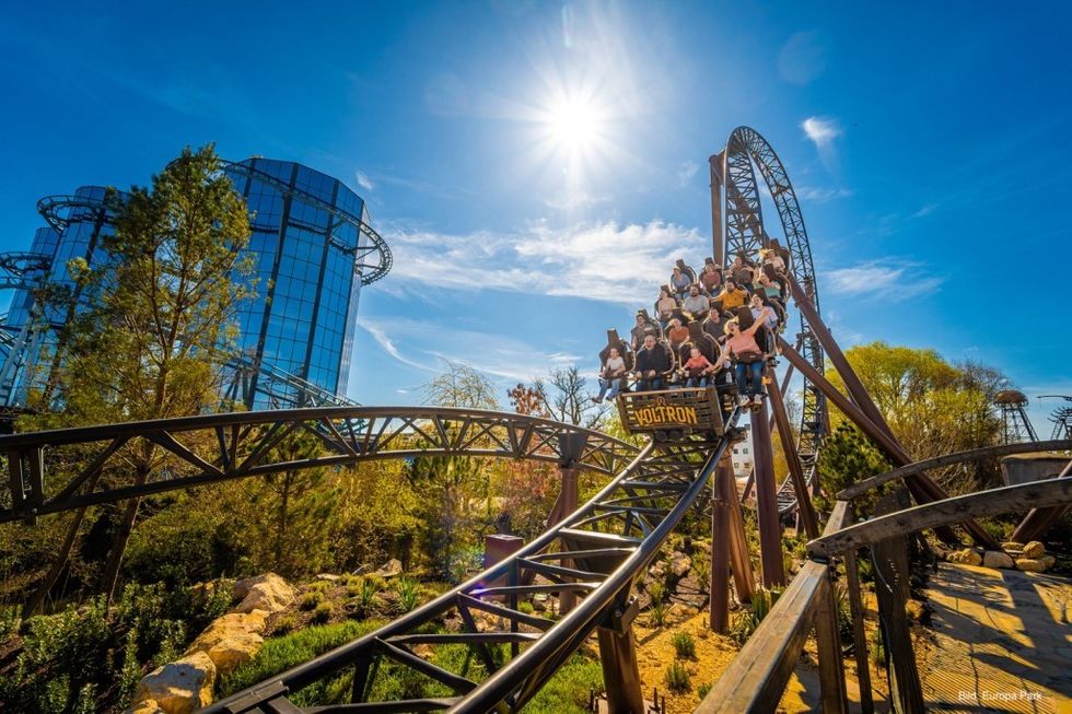 Voltron Nevera roller coaster ride on a sunny day with blue sky and trees in the background.