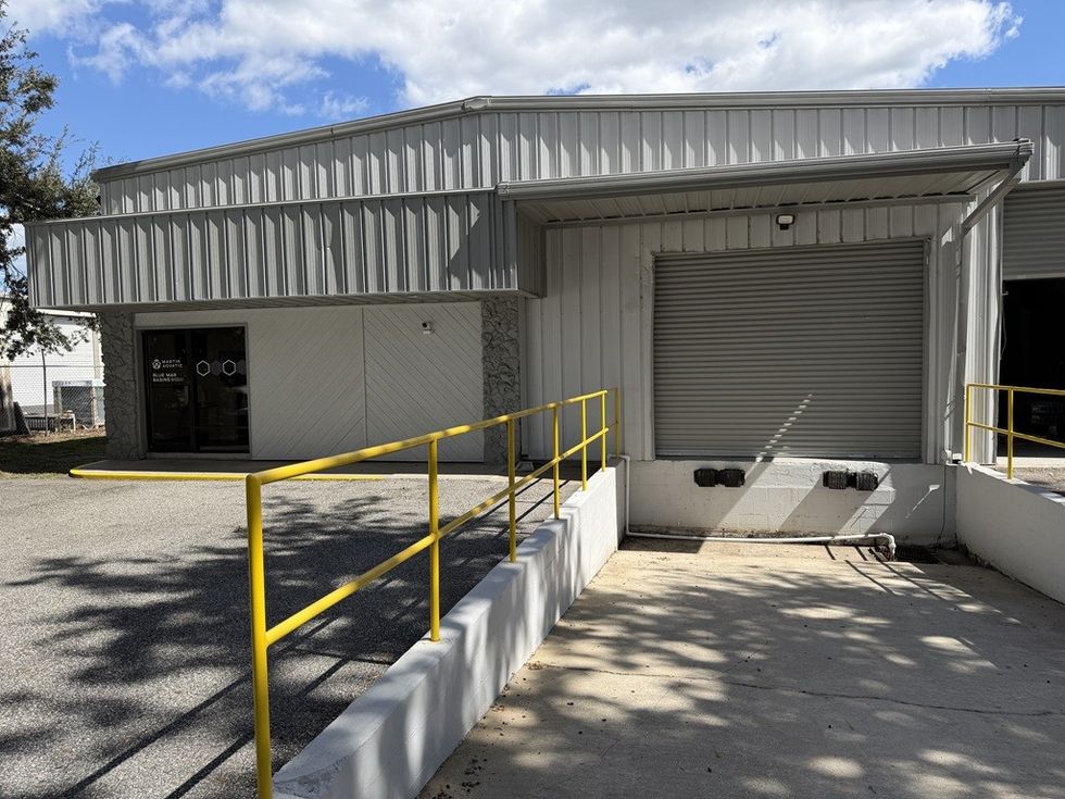 Warehouse entrance with yellow railings and a closed roll-up door.
