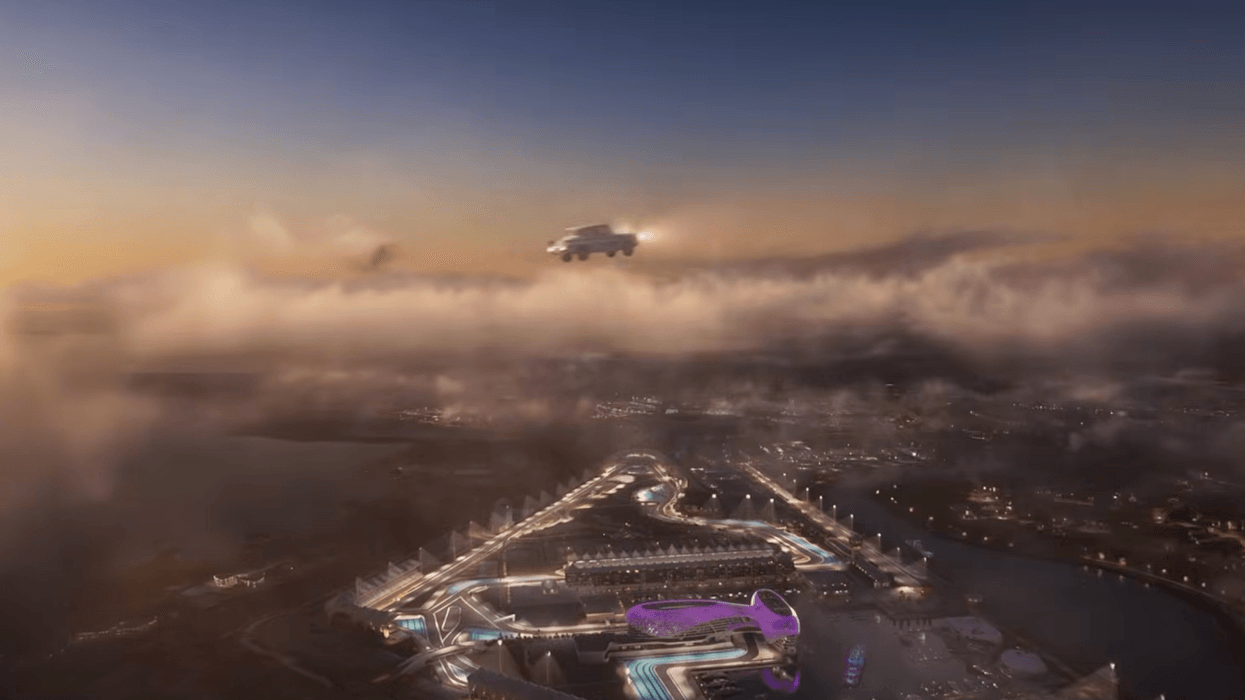 Warner Bros. World Abu Dhabi at dusk with Harry Potter flying car above illuminated racetrack and buildings.