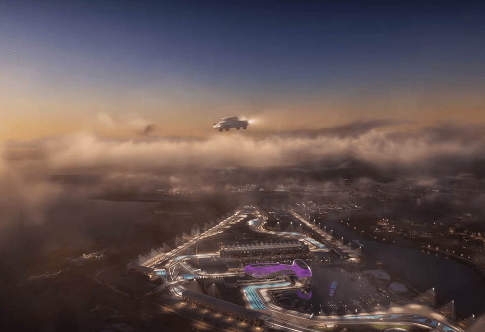 Warner Bros. World Abu Dhabi at dusk with Harry Potter flying car above illuminated racetrack and buildings.