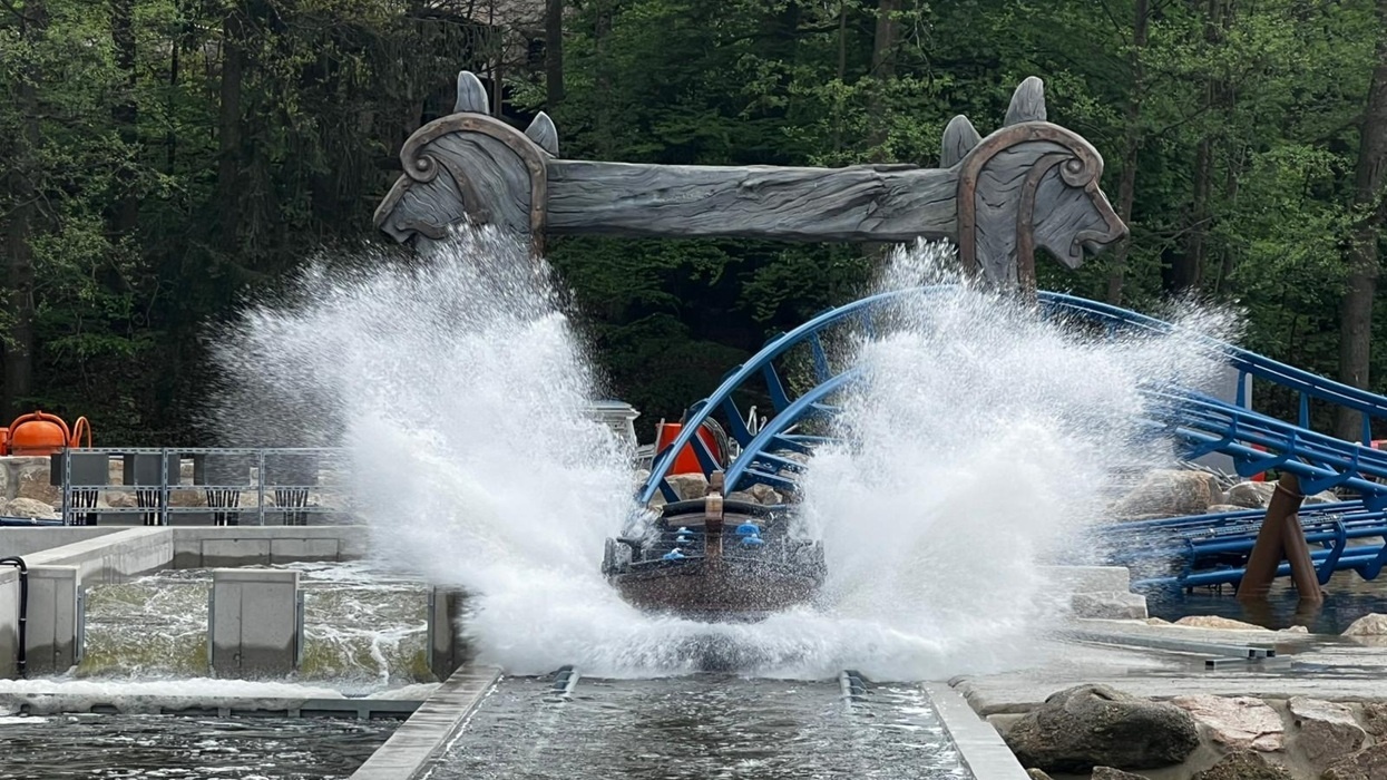 Water coaster splash in Donnervind at Freizeitpark Plohn, with blue tracks and sculpted wooden arch.