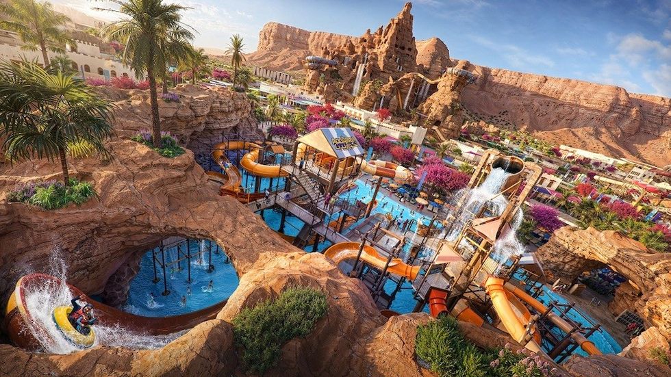 Water park called Aquarabia with slides, pools, palm trees, and desert mountain backdrop.