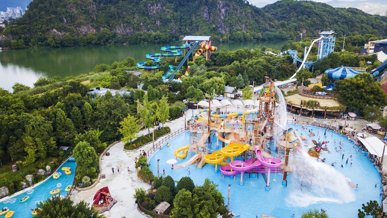 Water park with colorful slides surrounded by lush greenery near a scenic lake.