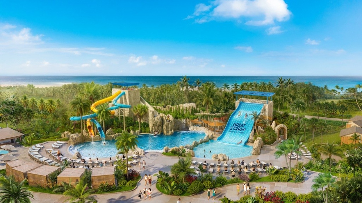 Water park with large slides by the beach, surrounded by palm trees and clear skies.