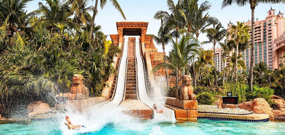 Water slide amid tropical trees with splashing rider at Aquaventure Water Park at Atlantis Paradise Island