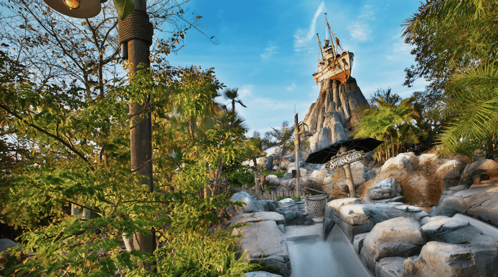 Water slide amidst lush greenery and rocks with a pirate ship atop a mountain at Disney's Typhoon Lagoon