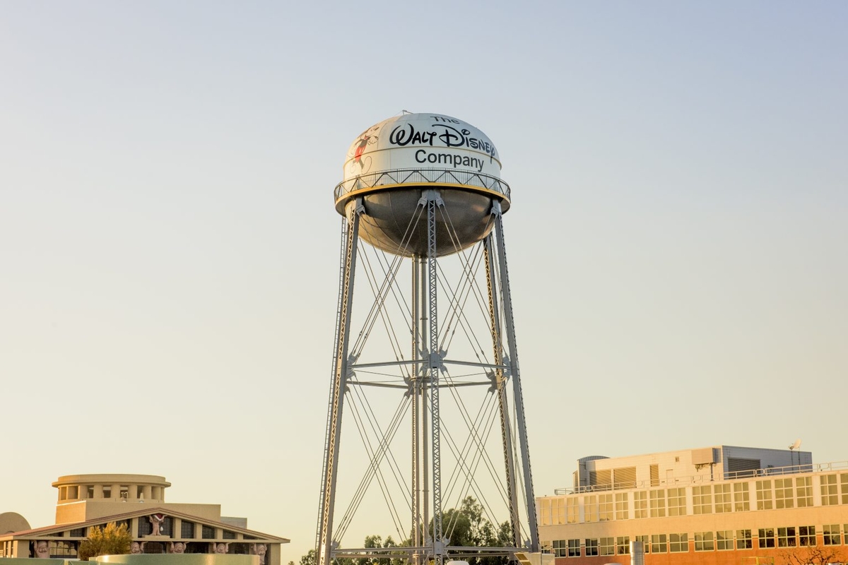 Water tower with "Walt Disney Company" logo against a clear sky.
