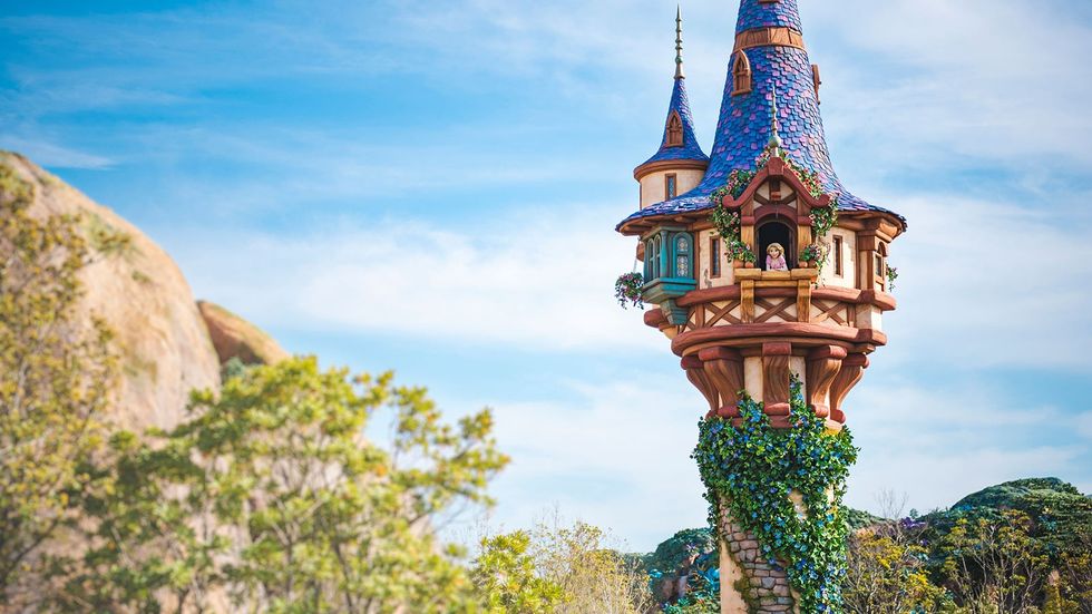 Whimsical tower with blue roof and ivy, set against a clear blue sky at tokyo disneysea