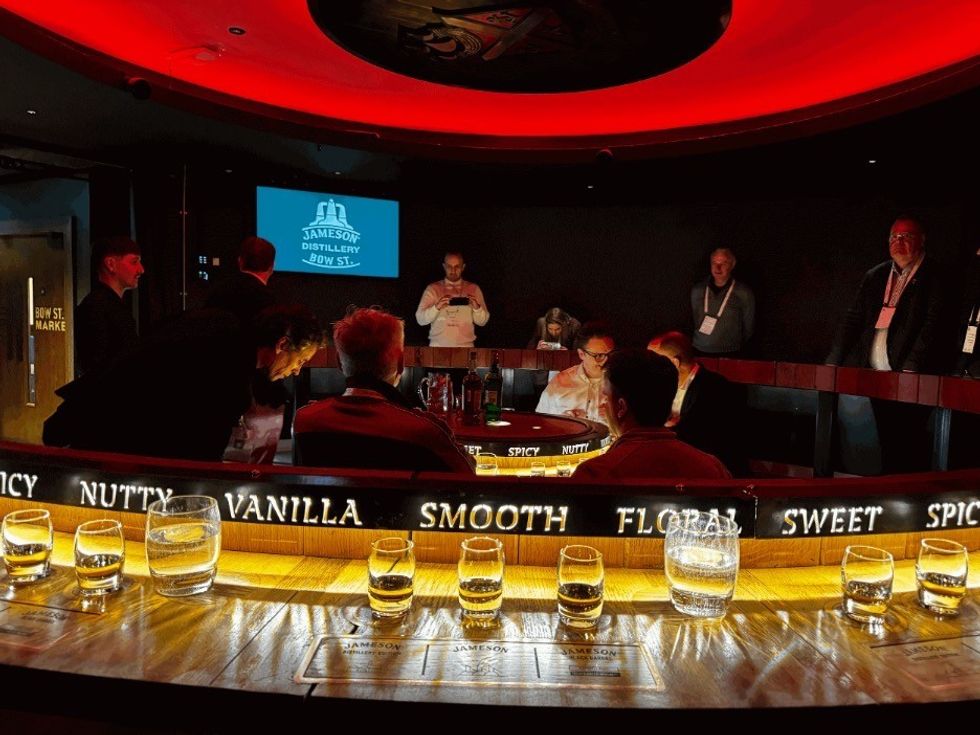 Whiskey tasting room at Jameson Distillery with people seated, illuminated notes, and multiple glasses on the table.
