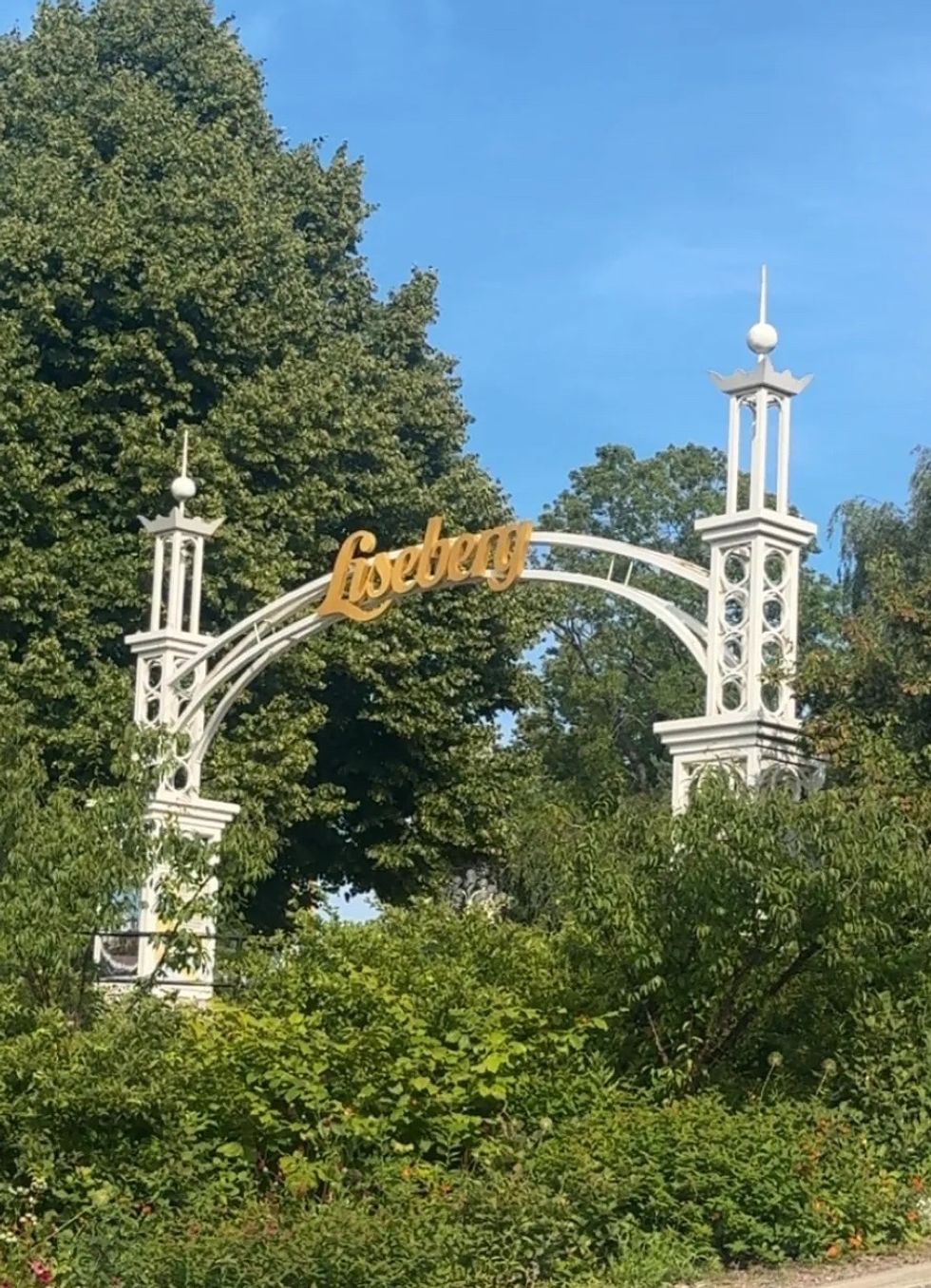 White archway with "Liseberg" sign set against trees and a blue sky.