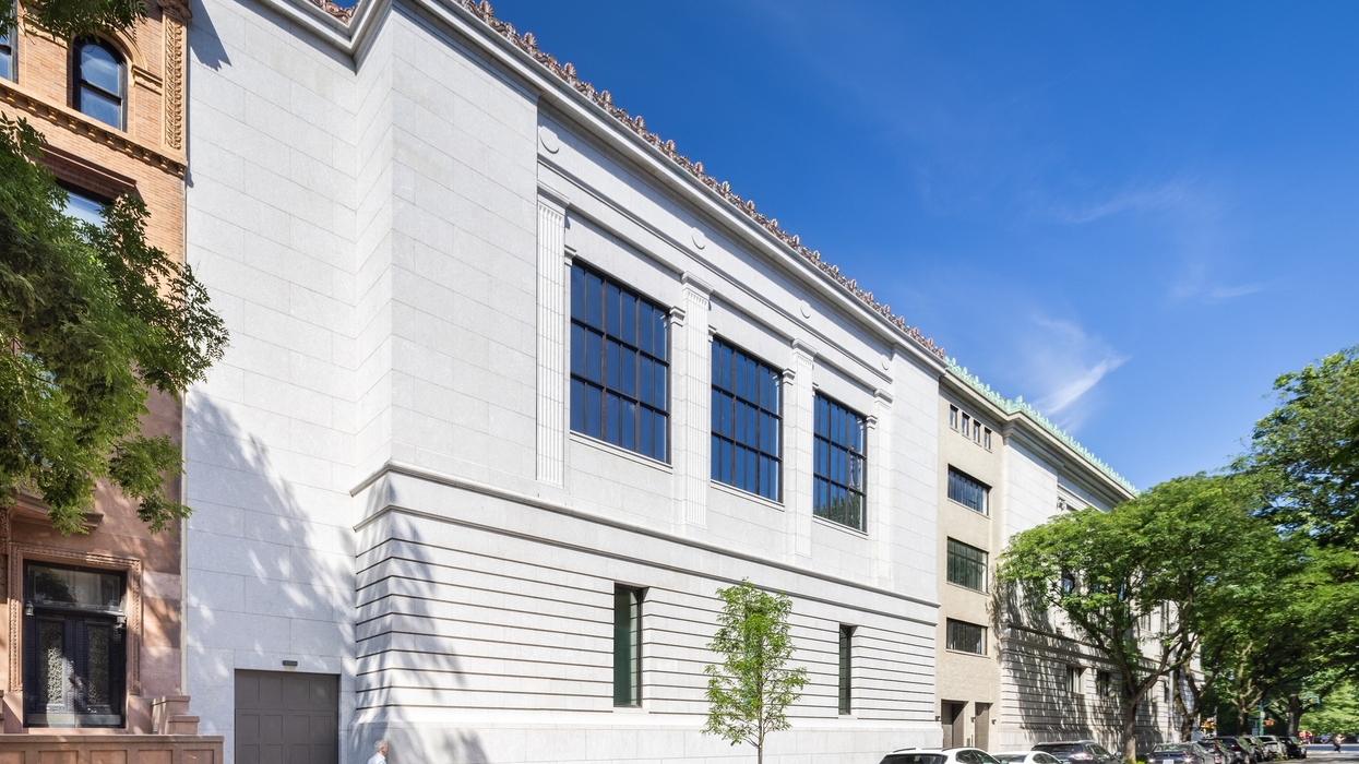 White building called the Tang Wing with tall windows on a sunny street, trees, and parked cars.