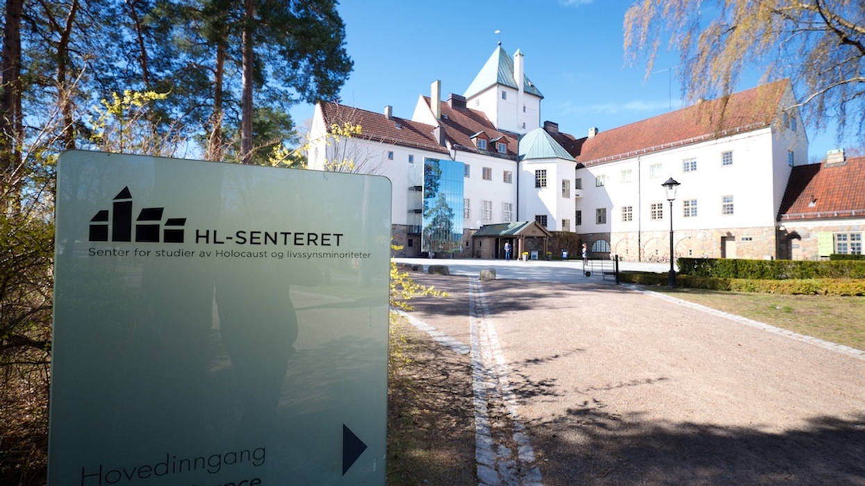 White building with sign for HL-Senteret, Holocaust studies center, under a blue sky.