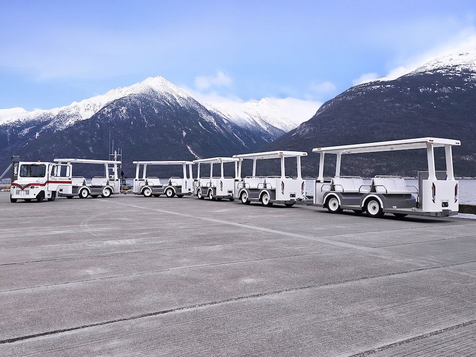 White open-air tram from Severn Lamb parked at Survey Point, Alaska, with snowy mountains in the background.