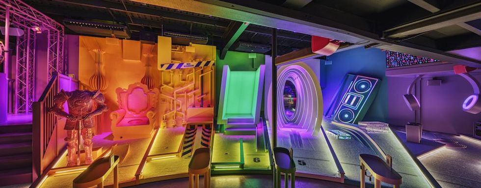 Wide view of BOXPARK Wembley Pop Golf mini course lit with rainbow lights