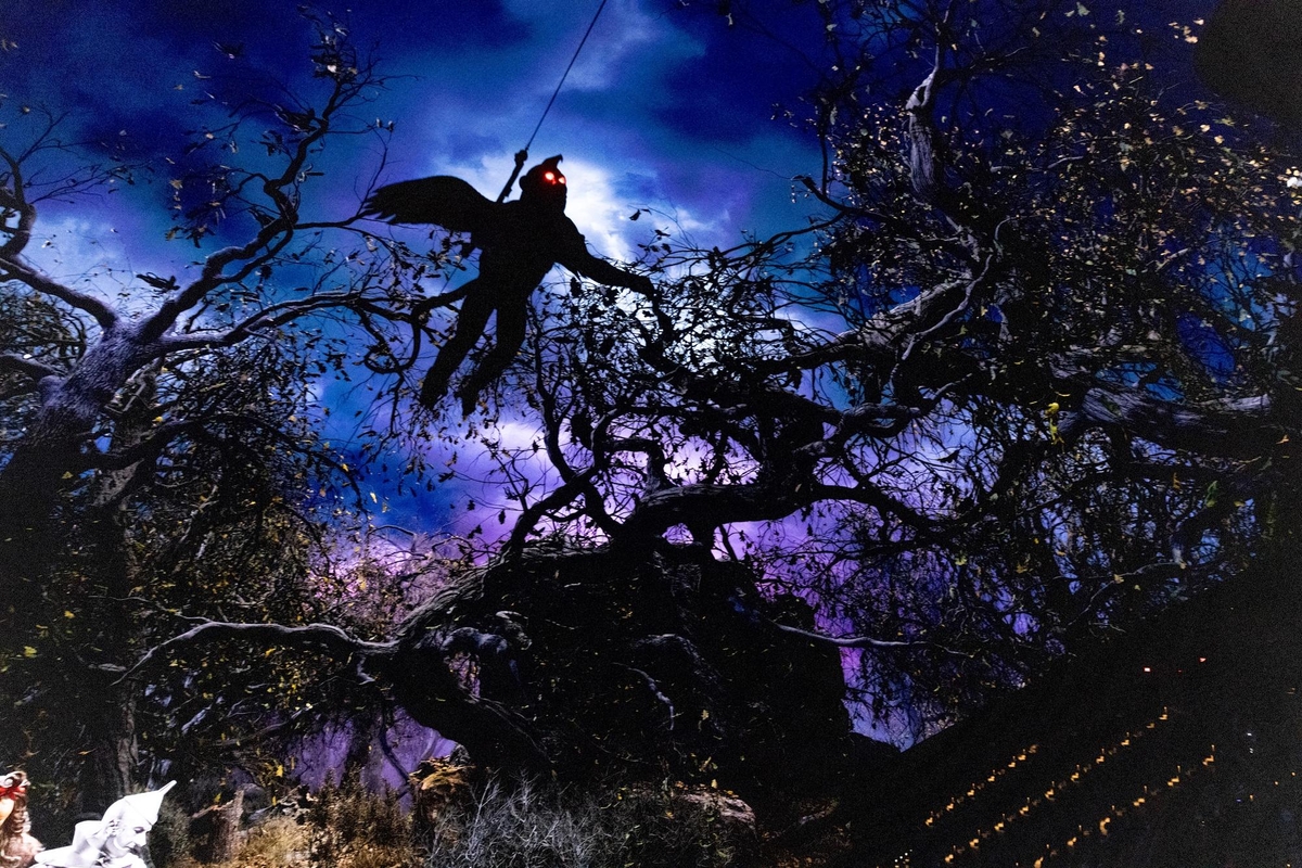 Winged Monkey with glowing eyes hangs among twisted trees against a moody, blue-purple sky
