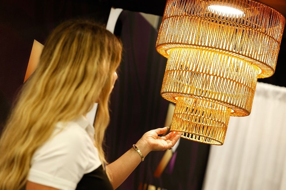 Woman admiring a large, woven, golden hanging light fixture.