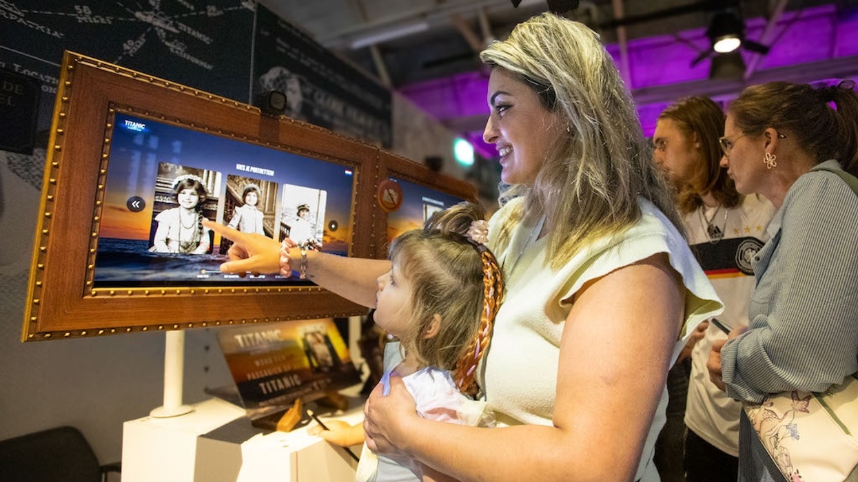 Woman and child interact with Titanic exhibit touchscreen photo souvenir booth from Citysaurus