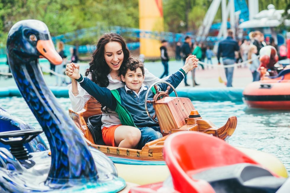 Woman and child smiling on a swan boat ride at an amusement park.