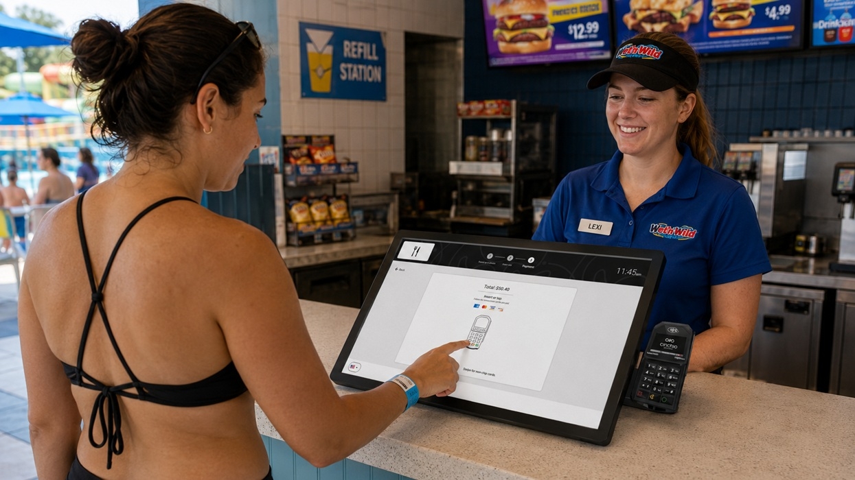 Woman at poolside snack bar using touchscreen to order food, employee smiling behind counter.