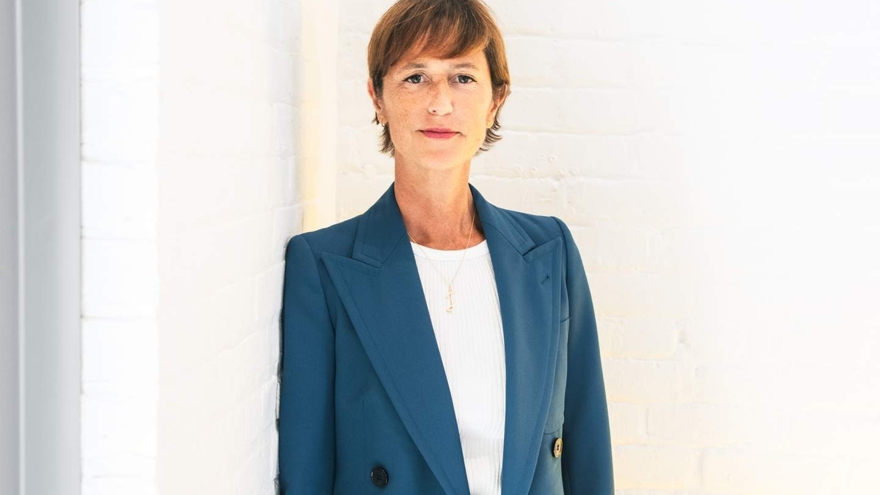 Woman called Jessica Morgan in a blue blazer leans against a white brick wall