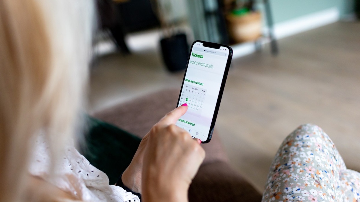 woman holiday a phone with Gantner ticketing app for Naturalis center