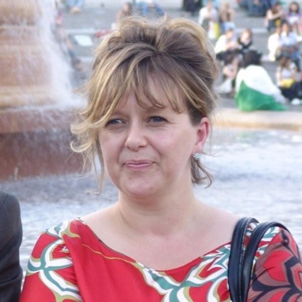 Woman in a colorful dress standing near a fountain.