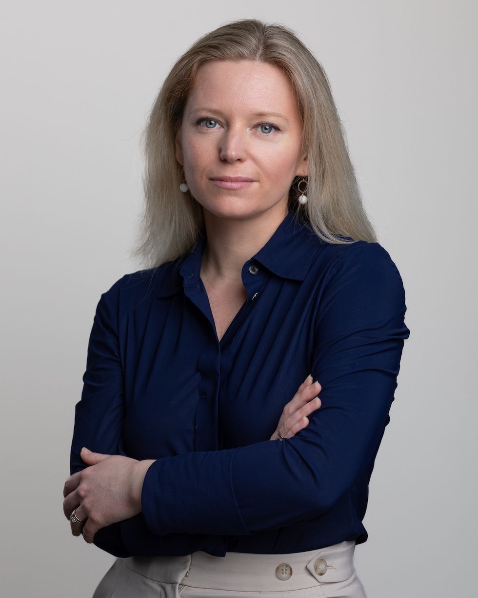 Woman in a navy blouse with arms crossed, looking confidently at the camera.