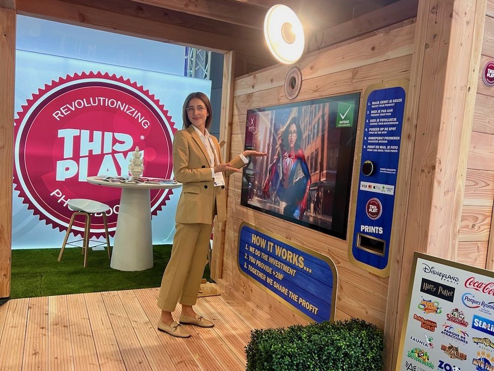 Woman in a suit presenting a photo booth at an exhibition stand.