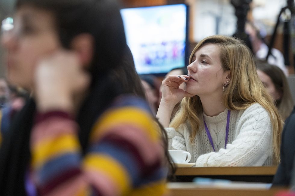 Woman in a sweater attentively listening during a conference or lecture.
