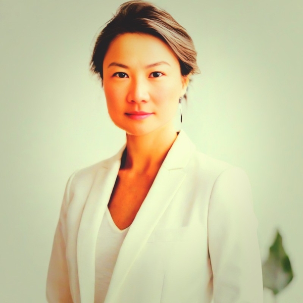 Woman in a white blazer with short hair, gazing confidently.
