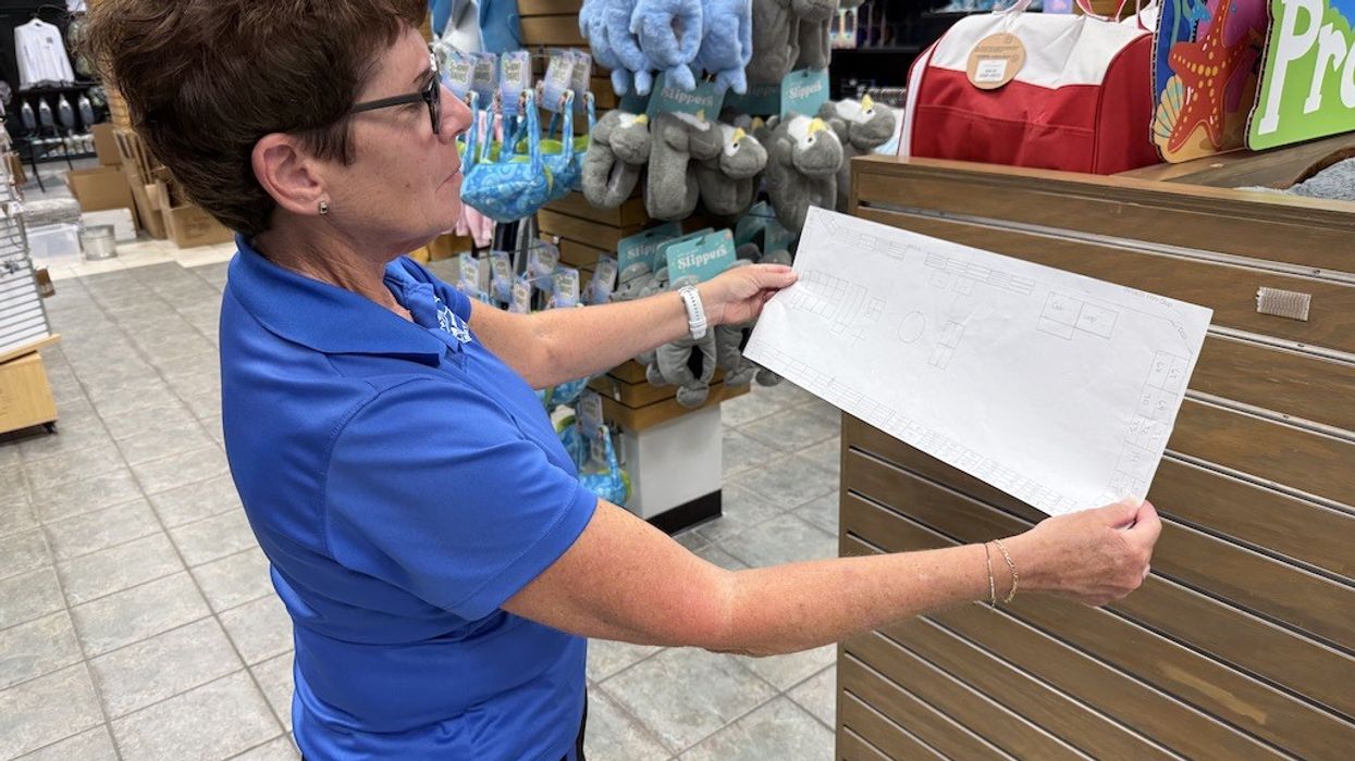 Woman in blue shirt examining a store layout plan in a retail location.