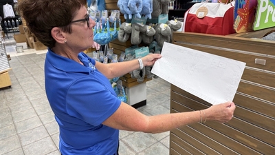 Woman in blue shirt examining a store layout plan in a retail location.