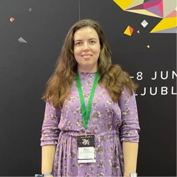 Woman in floral dress with lanyard at an event.