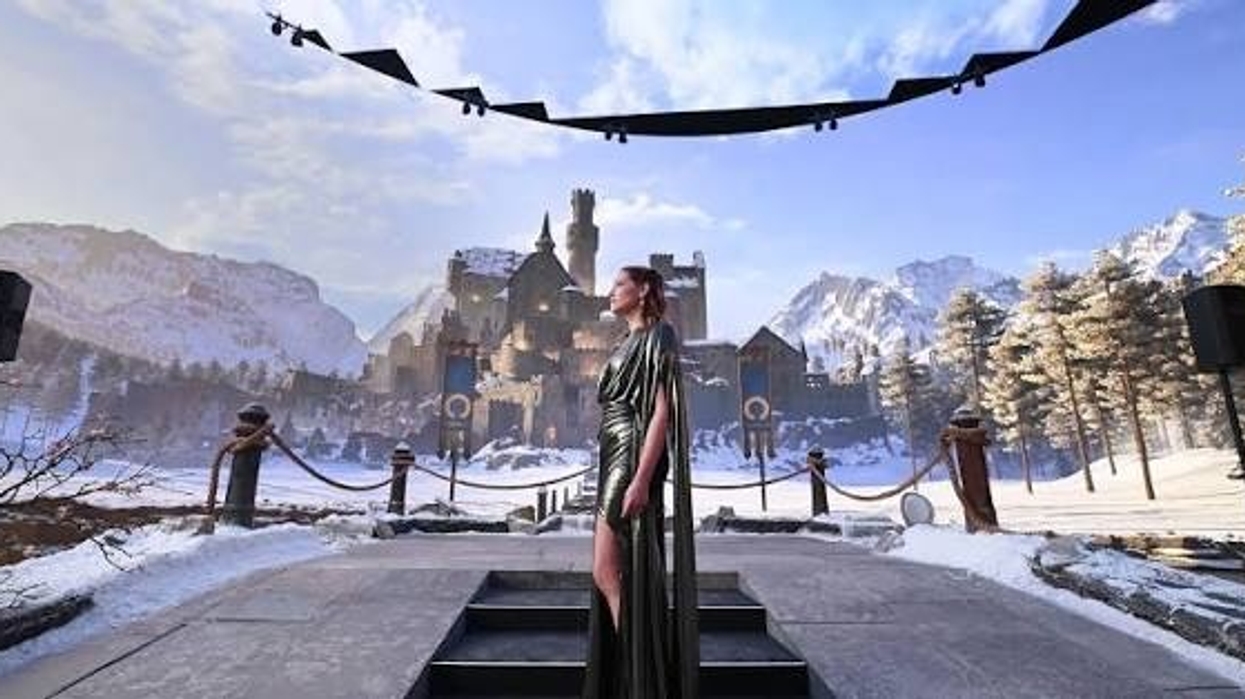 Woman in green dress stands before snowy castle under a clear sky.