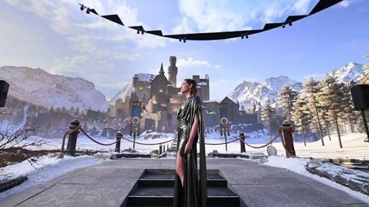 Woman in green dress stands before snowy castle under a clear sky.
