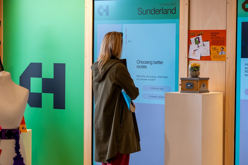 Woman interacting with a touchscreen display about choosing routes, standing in a modern exhibit.