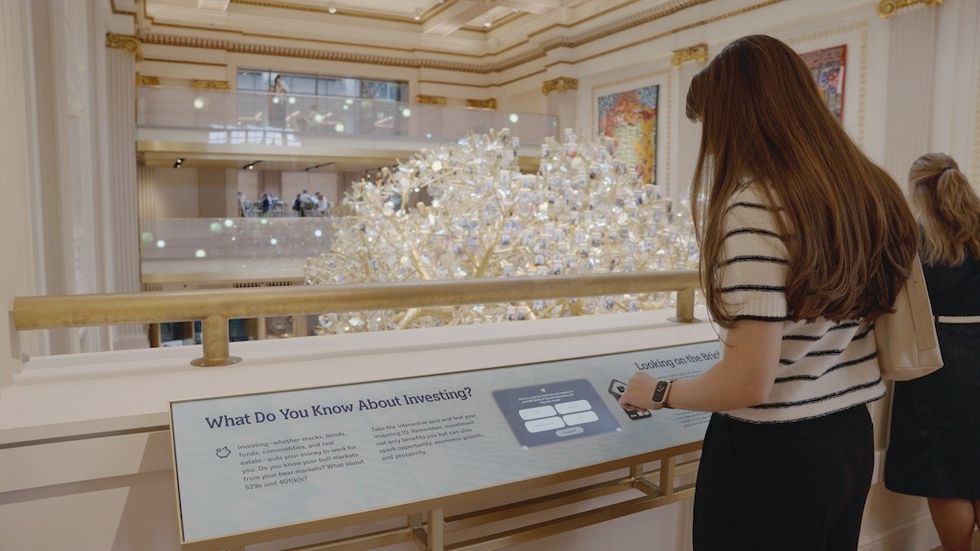 Woman interacting with an investment display in a grand, ornate hall.