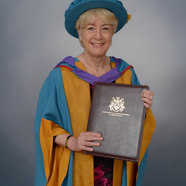 Woman named Linda Conlon in graduation attire holding a University of Northumbria diploma.