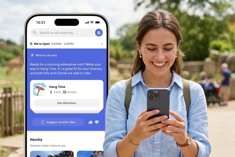 Woman outdoors at a theme park, using an Attractions.io smartphone app for directions to a ride.