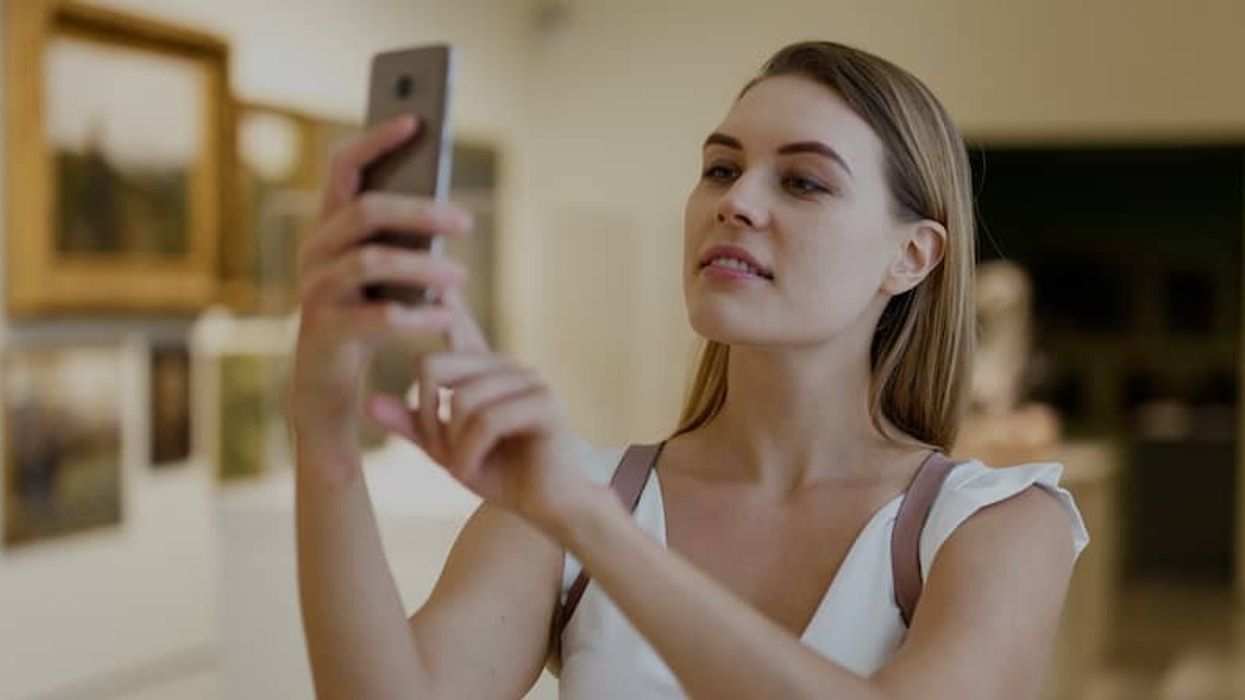 Woman photographing painting in museum mobile phone